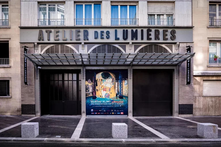 exterior of Atelier des Lumières in Paris with a poster for the Gustav Klimt immersive exhibition